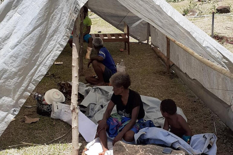 A group of people in Dreketi shelter under sheeting after cyclone damage to their home. A group of people in Dreketi shelter under sheeting after cyclone damage to their home.