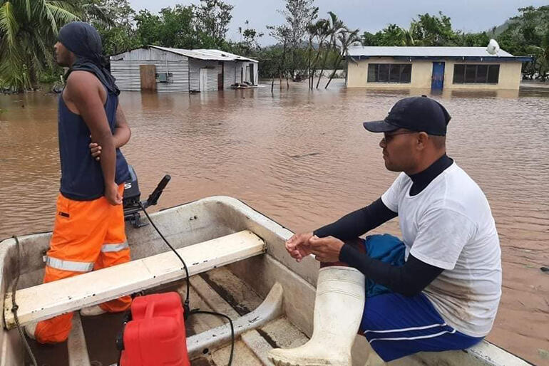 Two men patrol floodwaters looking for people needing a ride to safety in the aftermath of Cyclone Ana in Fiji this week.