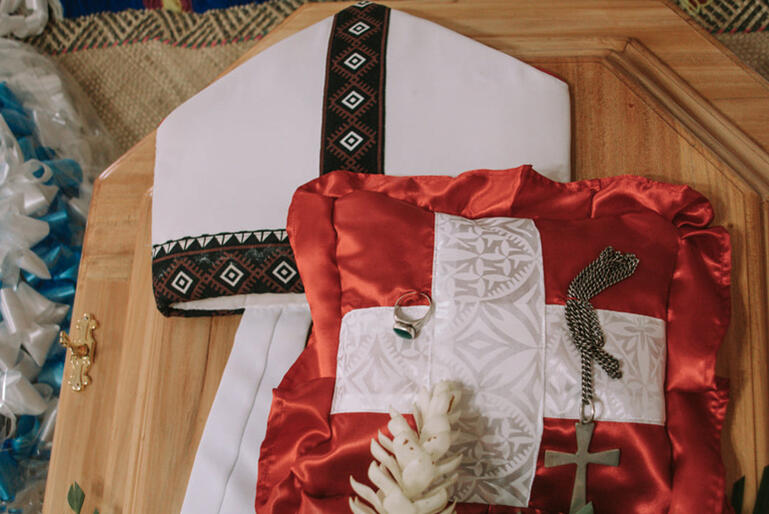 Archbishop Fereimi's symbols of episcopal office: his mitre, pectoral cross and episcopal ring, lie on his casket. Archbishop Fereimi's symbols of episcopal office: his mitre, pectoral cross and episcopal ring, lie on his casket.