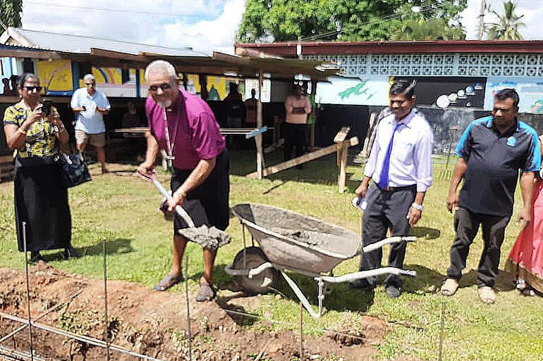 Bishop Henry Bull smiles for the camera as he wields a spadeful of cement headed for a classroom foundation at St Mary's Anglican School in Labasa.