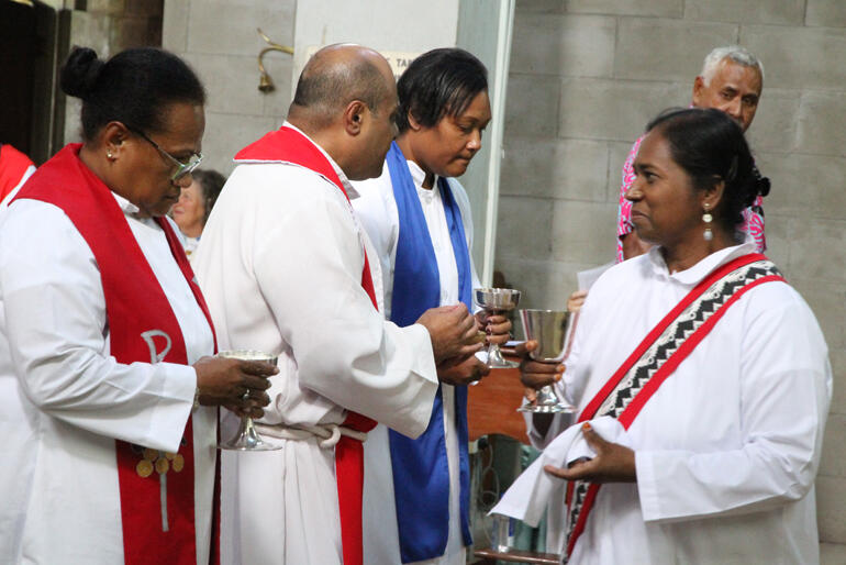 Deacon Rev Sushila Prasad returns to her spot next to Rev Louisa Smith after replenishing her chalice of wine. 