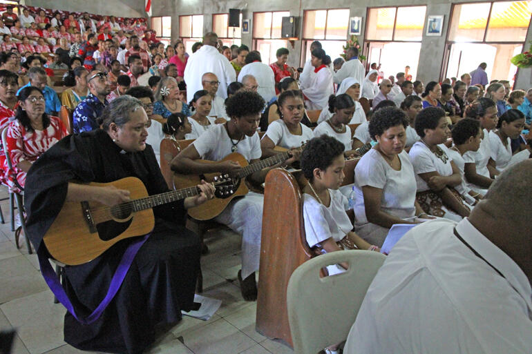 Rev Sepiuta Hala'api'api accompanies guitarists and singers from St Christopher's Home during Communion.