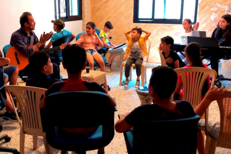 Palestinian refugee music teacher Osama teaches students at the Saida Centre, near the Ein El Hilweh UN refugee camp in Lebanon. Photo: CWS/DSPR.